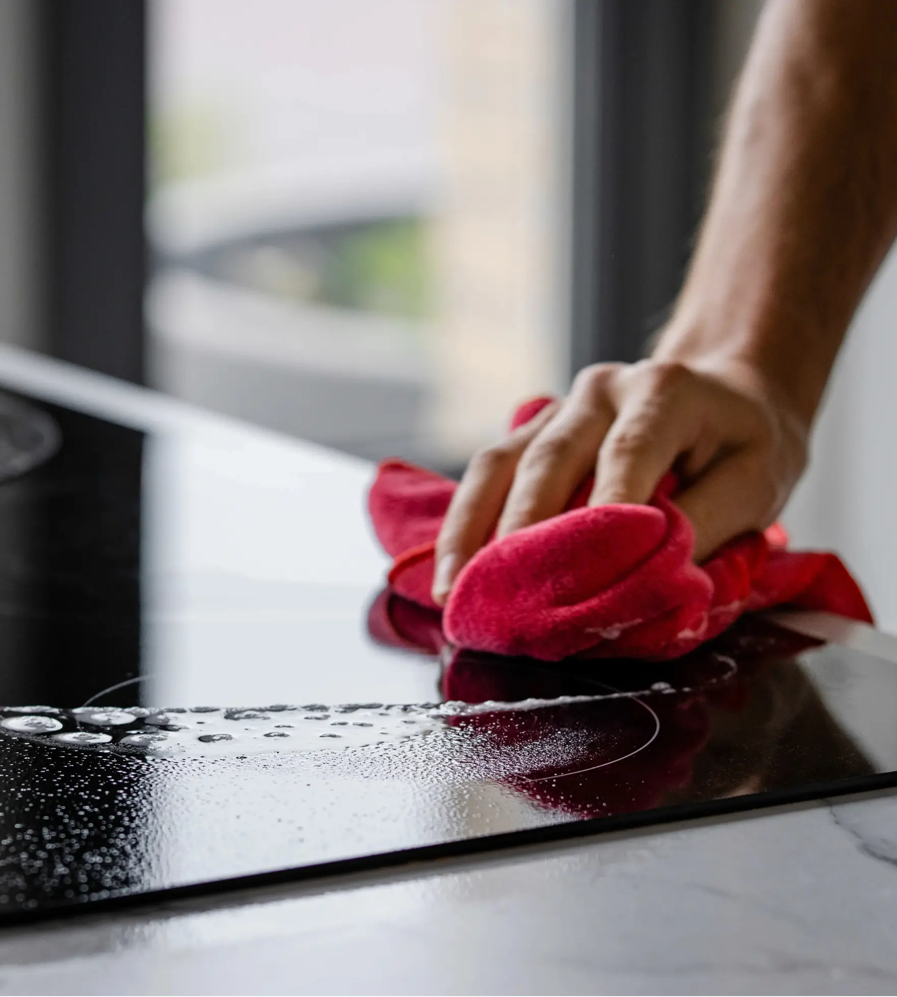 Iemand die met een microvezeldoek de kookplaat schoonveegt