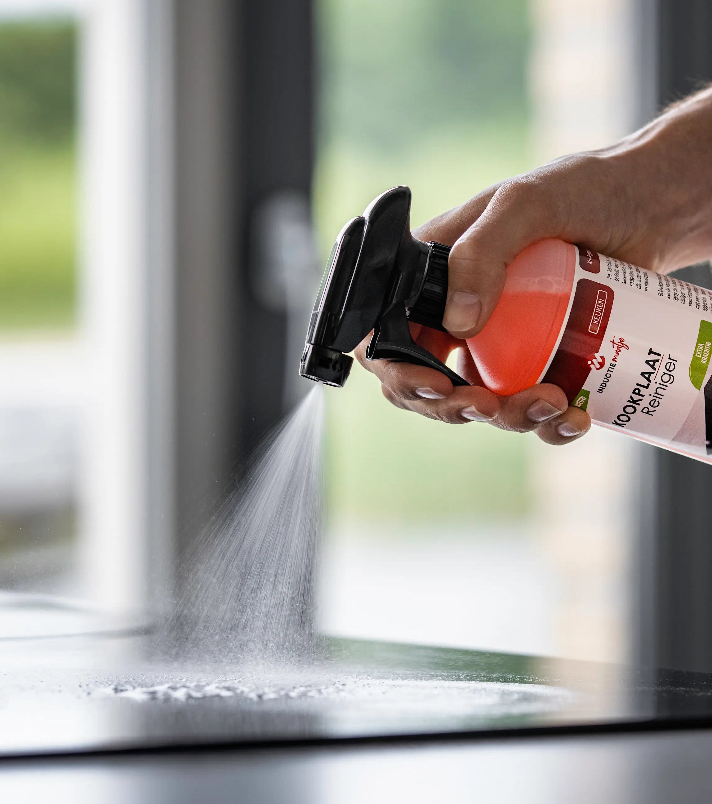 Iemand die een spray doet op een kookplaat met een kookplaat reiniger